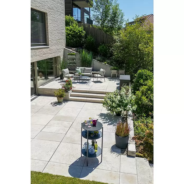 Sunfun Solo Mesa auxiliar de jardín redonda - Ø x Al: 65 x 108 cm, Acero, Gris - Carrito de bar de exterior redondo de varios niveles gris oscuro con bebidas y fruta en un patio.