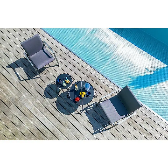 Sunfun Melina Garten-Beistelltisch rund - Ø x H: 80 x 60,5 cm, Stahl, Night-Grey - Luftaufnahme von zwei grauen Stühlen und zwei schwarzen Tischen auf einer Holzterrasse neben einem Pool mit Poolabdeckung.