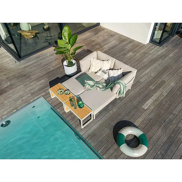Sunfun Solo Conjunto de muebles chaise lounge + mesa auxiliar - 4 pzs., Gris claro - Toma de ángulo alto de un juego de tumbona gris con mesas auxiliares, cojines y planta en una terraza de piscina.