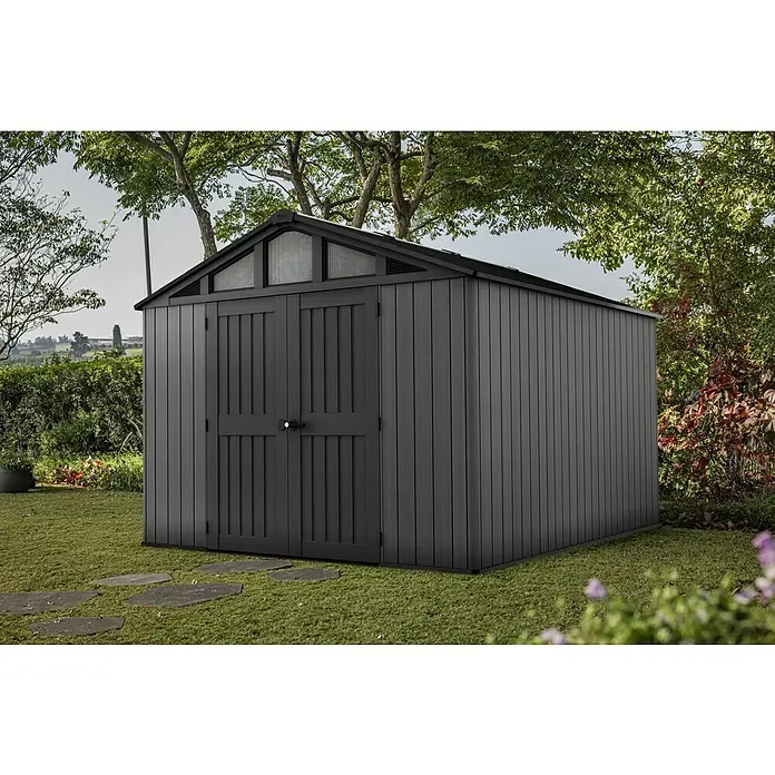 Keter Gerätehaus Stronghold 10x8 - Außenmaß inkl. Dachüberstand (B x T): 304 x 243 cm, Kunststoff, Grau - Graues Gartenhaus mit Doppeltüren und Oberlichtern im Giebel, umgeben von üppigem Grün und einem gepflegten Rasen.