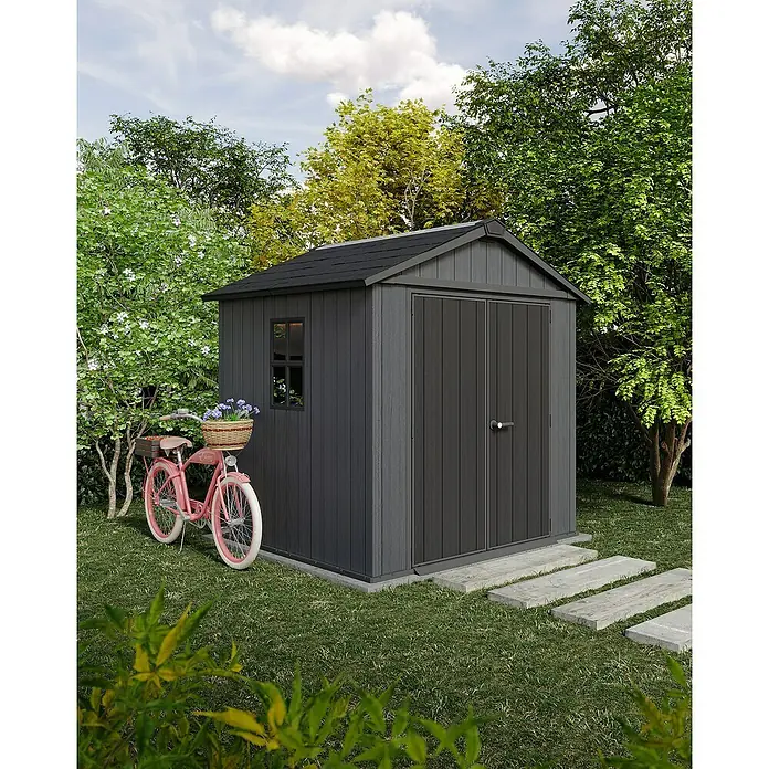 Keter Gerätehaus Newton Plus 757 - Außenmaß inkl. Dachüberstand (B x T): 230 x 223,8 cm, Kunststoff, Schiefergrau - Eine moderne, graue Gartengerätebox mit Doppeltür und einem kleinen Fenster, ergänzt durch ein rosa Fahrrad mit Blumenkorb.