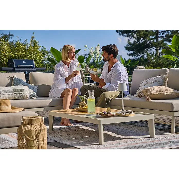 Sunfun Solo Mesa auxiliar de jardín - L x An x Al: 120 x 72 x 26 cm, Aluminio, Rectangular, Gris/Beige - Una pareja relajada disfruta de bebidas refrescantes al aire libre en un conjunto de patio gris con mesa a juego.