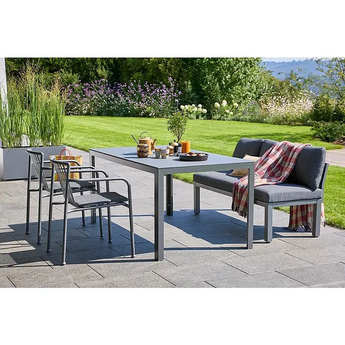 Sunfun Gartenmöbel-Set Maja/Sarah - 4 -tlg., Aluminium, Stahl, Sicherheitsglas, Night-Grey - Ein graues Gartenset mit einem Tisch, Stühlen und einer Bank auf einer Terrasse, umgeben von Grün. Elegantes Design für den Außenbereich.
