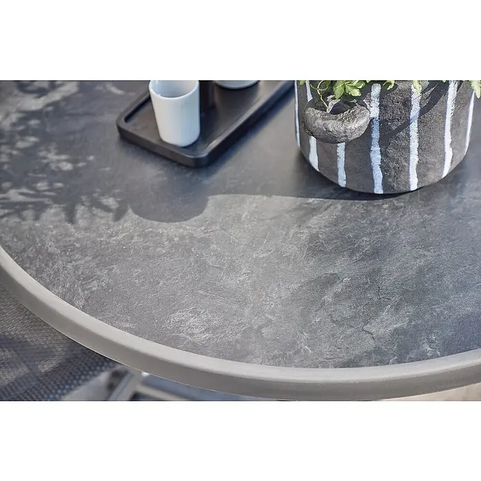 MFG Balkontisch rund Boulevard - Ø x H: 70 x 110 cm, Stahl, Mecalit, Klappbar, Anthrazit - Nahaufnahme eines grauen Gartentisches mit dekorativer Pflanze und Geschirr, ideal für entspannte Stunden im Freien.