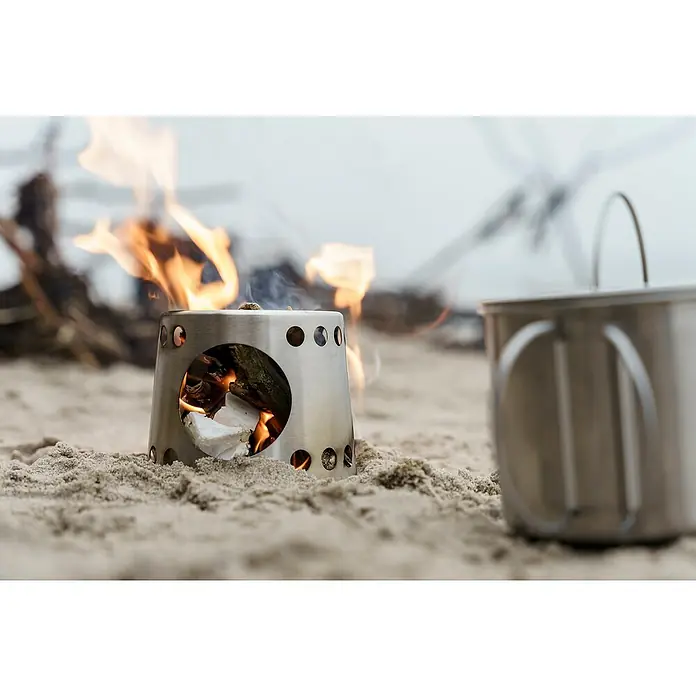 Petromax Kochbecher - Edelstahl - Lagerfeuerstelle aus Edelstahl auf Sand mit Kochtopf. Ideal für Camping und Outdoor-Abenteuer, kompakt & robust.