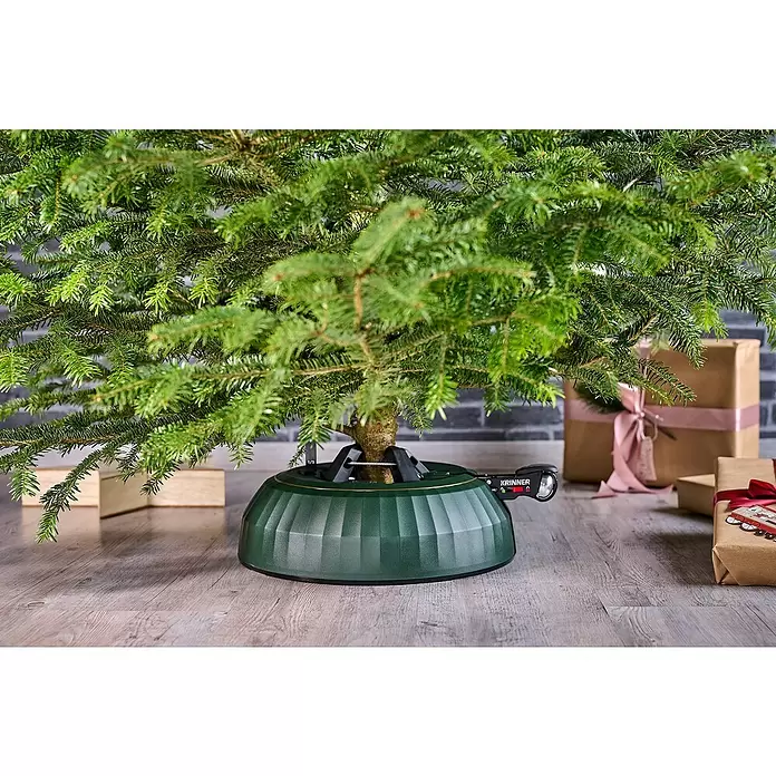 Krinner Christbaumständer X-280 Deluxe - 37 x 11,5 cm, Kunststoff, Rund - Dunkelgrüner Weihnachtsbaumständer mit Hebelmechanismus, der einen frischen Tannenbaum sicher hält, umgeben von Geschenken.
