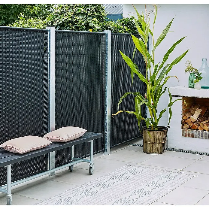 Plus Zaunpfosten - 268 cm x 80 mm x 80 mm, Silber, Stahl - Stilvolle Gartenszene mit einem schwarzen Sichtschutzzaun, einer grauen Bank mit Kissen und einem dekorativen Maispflanzgefäß auf einer Terrasse.