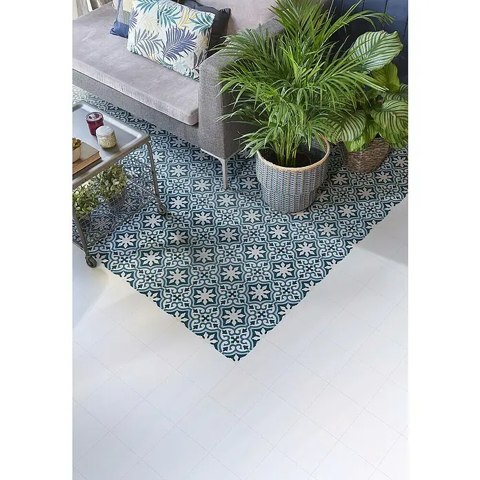 Feinsteinzeugfliese Barcelona Blanco - 24,8 x 24,8 cm, Weiß, Matt - Ein Arrangement mit einem Sofa, Beistelltisch und Zimmerpflanzen auf einem stilvollen Vinylboden mit floralem Muster.