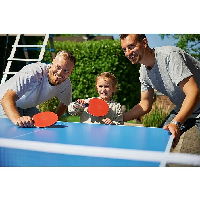 Hudora Tischtennisplatte Match - Blau - Familie spielt Tischtennis im Garten, lachend und mit Spaß an der Bewegung, während die Sonne scheint und gute Laune verbreitet.
