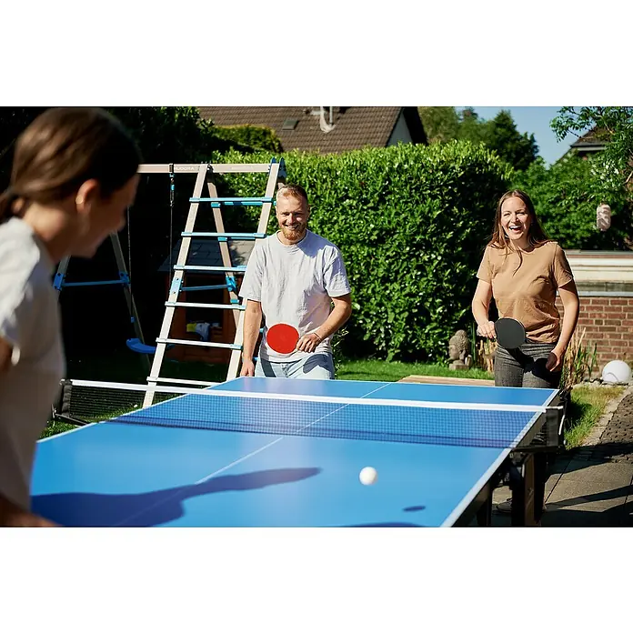 Hudora Tischtennisplatte Match - Blau - Drei Personen spielen Tischtennis im Freien. Der Tischtennistisch ist blau mit einem Netz in der Mitte für ein spannendes Spiel.