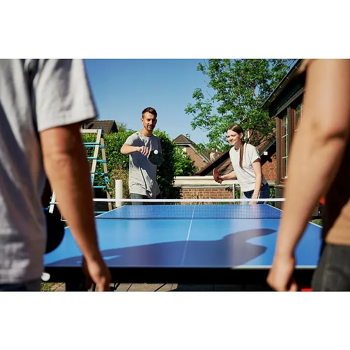 Hudora Tischtennisplatte Match - Blau - Eine lebendige Aufnahme von Personen, die im Freien an einem blauen Tischtennisspieltisch spielen, der die Freude an sportlicher Betätigung im Freien vermittelt.