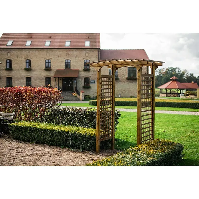 Pergola Straßburg - Durchgangsbreite: 100 cm, Höhe: 218 cm - Nahaufnahme eines dekorativen Holzbogens im Garten, der einen rustikalen Charme mit sorgfältig geschnittenen Hecken und einem eleganten Pavillon verbindet.