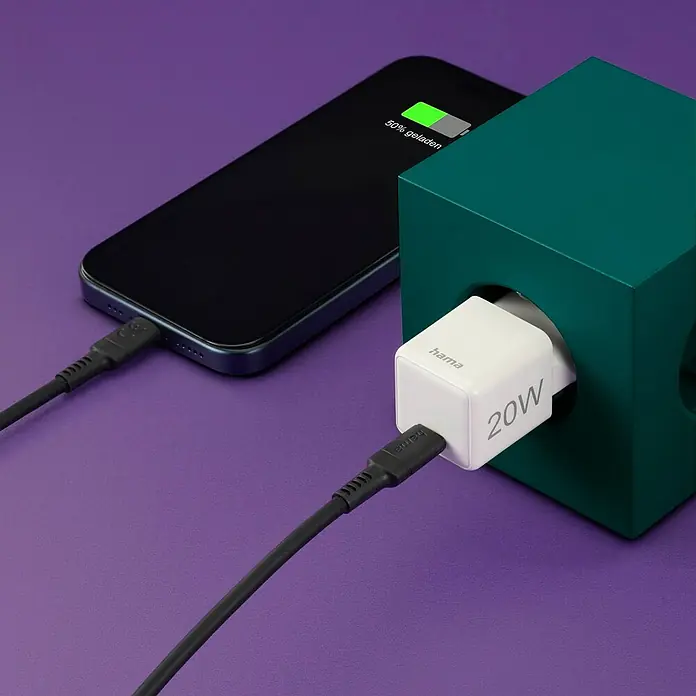 Hama USB-Adapter Schnellladegerät - 20 W, Weiß, USB C-Stecker - Das Bild zeigt ein Hama 20W USB-C Ladegerät in einem grünen Würfel, das ein Smartphone auflädt. Das Ladegerät ist weiß und kompakt.