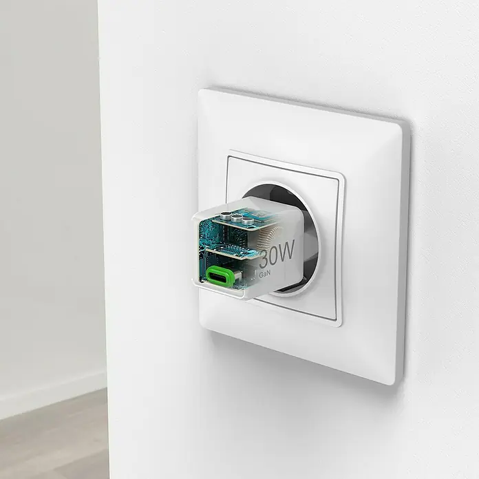 Hama USB-Adapter Schnellladegerät - 30 W, Weiß, USB C-Stecker - Eine Nahaufnahme eines 30W GaN Ladegeräts, das in eine weiße Steckdose an einer weißen Wand gesteckt ist, mit Blick auf die interne Platine.
