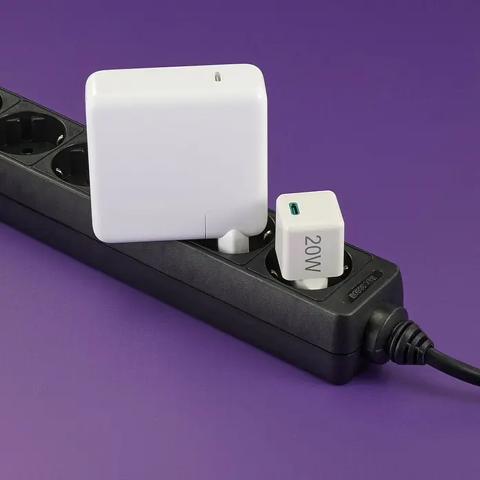 Hama USB-Adapter Schnellladegerät - 20 W, Weiß, USB C-Stecker - Nahaufnahme von zwei weißen USB-C-Netzteilen, die an einer schwarzen Steckdosenleiste mit Kabel auf violettem Hintergrund angeschlossen sind.
