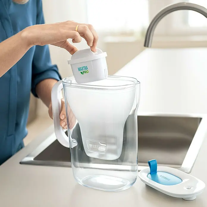 Brita Jarra filtrante Maxtra Pro - Capacidad volumétrica: 2,4 l, 1 ud., Transparente/Azul - Una persona inserta un filtro Brita Maxtra Pro blanco en una jarra de filtro de agua Brita transparente para purificar el agua.