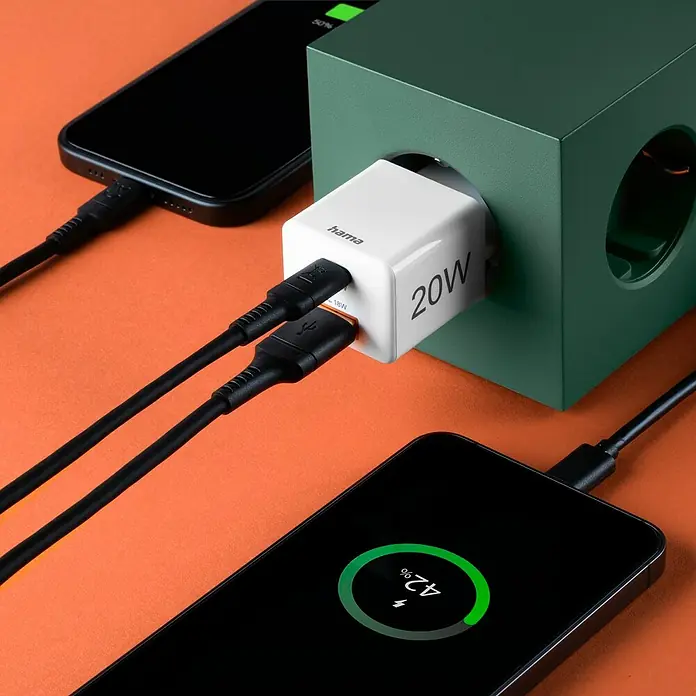 Hama USB-Adapter Schnellladegerät USB-C+A - Weiß, 20 W - Das Bild zeigt ein Hama 20W Ladegerät mit zwei angeschlossenen Smartphones, die geladen werden. Der Fokus liegt auf dem praktischen Ladegerät.