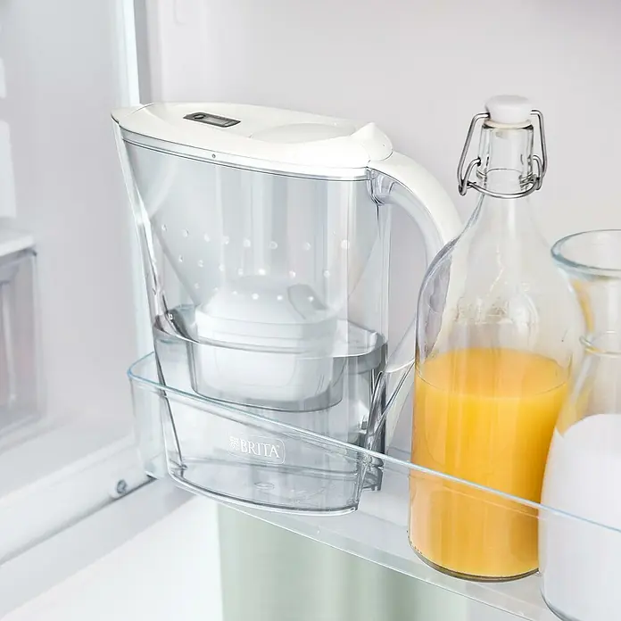 Brita Jarra filtrante Marella - Capacidad volumétrica: 2,4 l, 1 ud., Transparente/Blanco - Una jarra de filtro de agua Brita y botellas de vidrio con bebidas en la nevera. La jarra Brita filtra el agua de forma rápida y fiable.