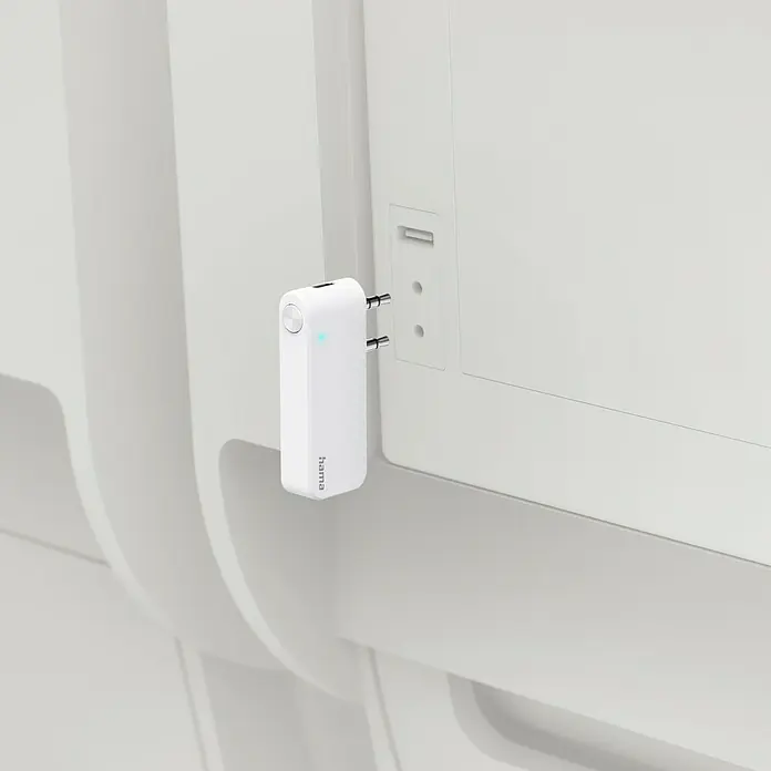 Hama Audio-Adapter Transmitter für Flugzeuge - USB-C-Buchse - Das Bild zeigt einen weißen Hama-WLAN-Repeater, der in eine weiße Steckdose an einer weißen Wand eingesteckt ist.