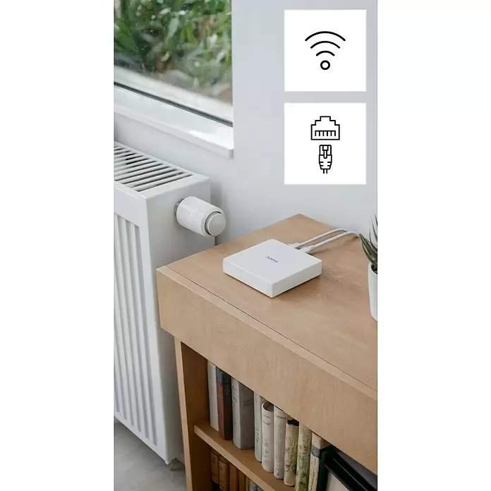 Hama Steuerzentrale Smart-Home-Hub, Matter für Sprach- / Appsteuerung - Weiß - Weißes Smart-Home-Gateway auf Holzregal neben Heizkörper mit Thermostat, verbunden über WLAN und Ethernet.
