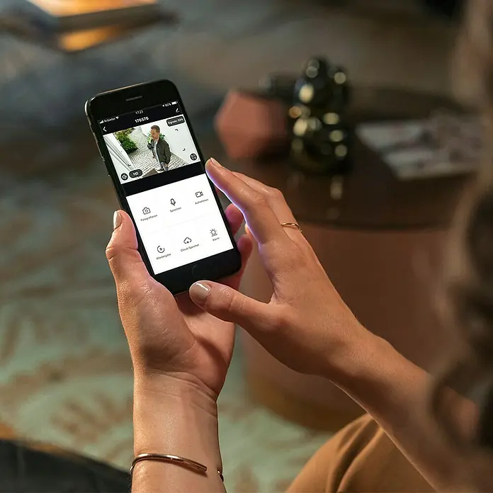 Hama Wifi Überwachungskamera 176645 - Erfassungswinkel: 110 ° - Frau bedient eine Überwachungskamera-App auf einem Smartphone. Überwachung zu Hause ist jetzt einfach!
