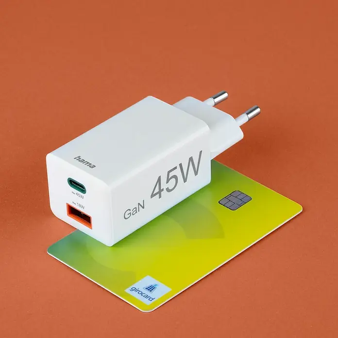 Hama USB-Adapter Schnellladegerät USB-C+A - Weiß, 45 W - Nahaufnahme eines weißen Hama GaN 45W USB-C-Ladegeräts, das auf einer Girocard vor einem orangefarbenen Hintergrund platziert ist.