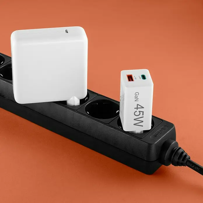 Hama USB-Adapter Schnellladegerät USB-C+A - Weiß, 45 W - Ein schwarzer Stromverteiler mit zwei weißen Ladegeräten, eines mit der Aufschrift "GaN 45W", auf einem orangefarbenen Hintergrund.
