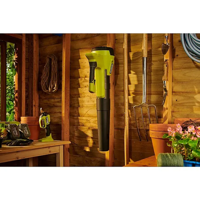 Ryobi ONE+ Akku-Gebläse RY18BLB-0 - 18 V, Ohne Akku, Blasgeschwindigkeit: 160 km/h - Eine Nahaufnahme eines RYOBI Akku-Laubbläsers in einer Hütte, der eine bequeme und effiziente Gartenarbeit ermöglicht.