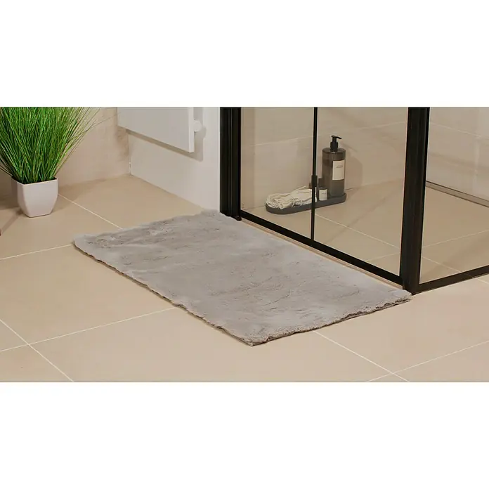 Badteppich Happy - 50 x 90 cm, Silber, 100% Polyester - Weicher, grauer Badteppich vor einer Duschkabine auf hellen Fliesen. Der Teppich bietet Komfort und Stil im Badezimmer.