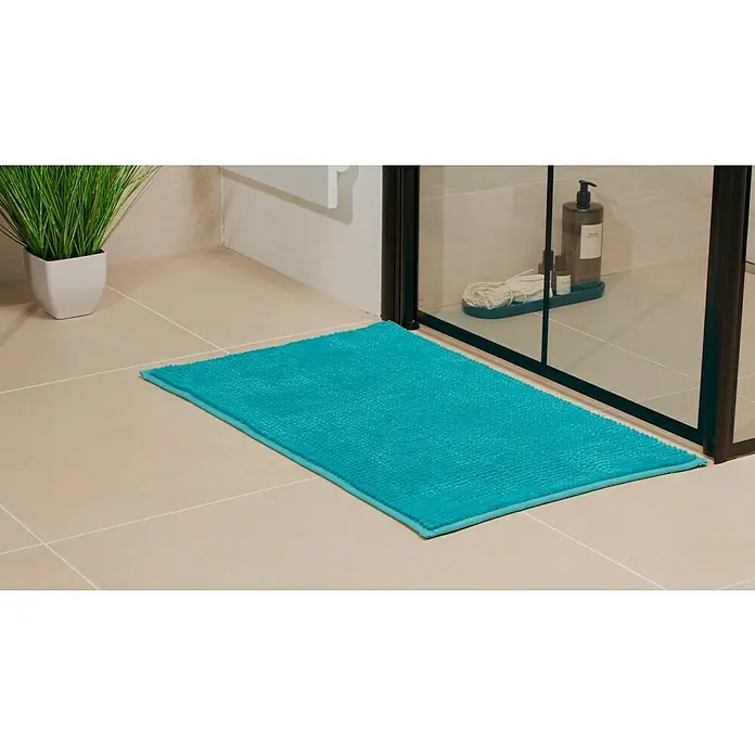 Camargue Badteppich Zottel - 50 x 80 cm, Aqua, 100% Polyester - Nahaufnahme einer türkisfarbenen Badematte auf Fliesenboden, neben einer Dusche und einer Topfpflanze.