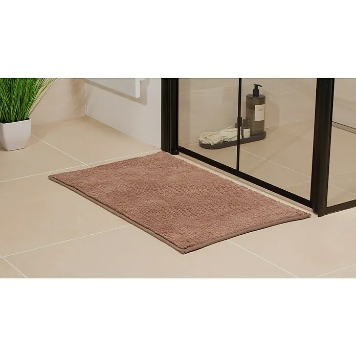 Camargue Badteppich Zottel - 50 x 80 cm, Braun, 100% Polyester - Ein brauner Badteppich liegt vor einer Duschkabine auf beigen Fliesen und bietet Komfort und Sicherheit nach dem Duschen.