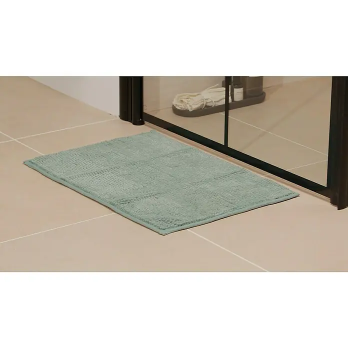 Badteppich Bubble - 40 x 60 cm, Blau, 100% Polyester - Ein hellgrüner Badteppich liegt vor einer Duschkabine auf hellen Fliesen und sorgt für Komfort und Sicherheit im Badezimmer.