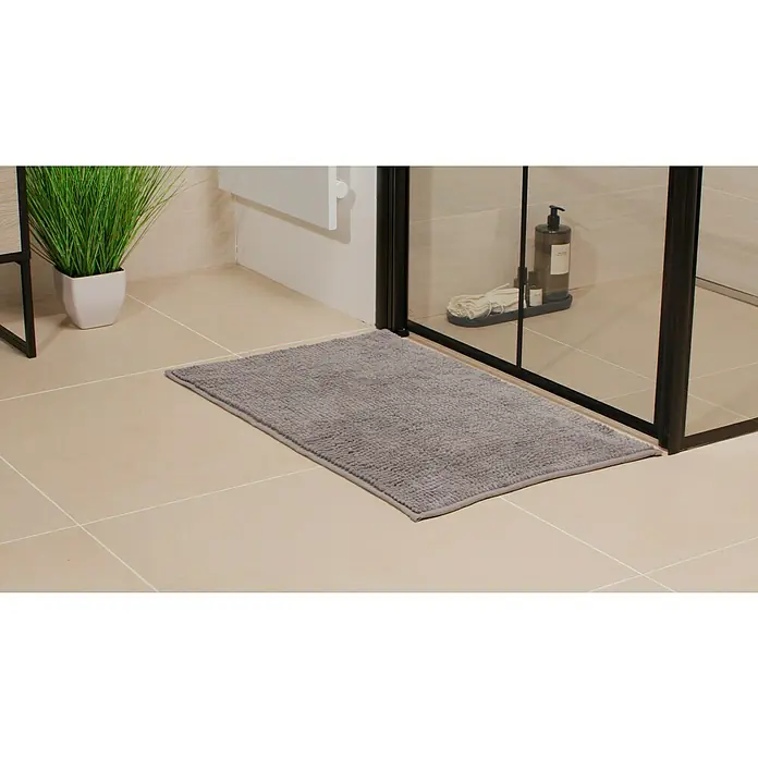 Camargue Badteppich Zottel - 50 x 80 cm, Grau, 100% Polyester - Ein grauer, rechteckiger Badteppich liegt vor einer Duschkabine auf hellen Fliesen und bietet Komfort und Sicherheit nach dem Duschen.