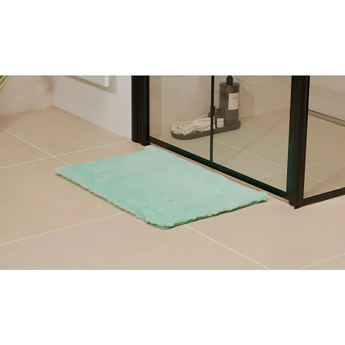 Badteppich Happy - 40 x 60 cm, Mint, 100% Polyester - Badezimmeransicht mit einer mintgrünen Badematte vor einer Duschkabine, die für Komfort und Stil in der Badezimmerausstattung sorgt.