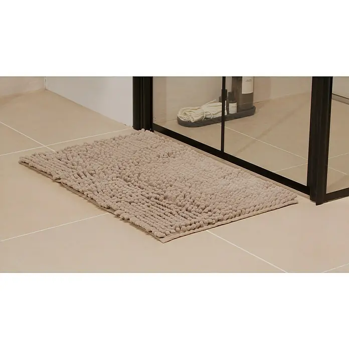 Badteppich Bubble - 45 x 75 cm, Dune, 100% Polyester - Weiche, rechteckige Badematte in Beige liegt vor einer Duschkabine und sorgt für Komfort und Sicherheit im Badezimmer.