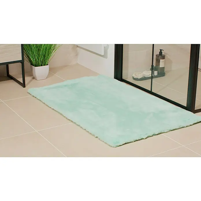 Badteppich Happy - 67 x 110 cm, Mint, 100% Polyester - Ein weicher, mintgrüner Teppich liegt im Badezimmer vor der Dusche und sorgt für Komfort und Stil auf den Fliesen.