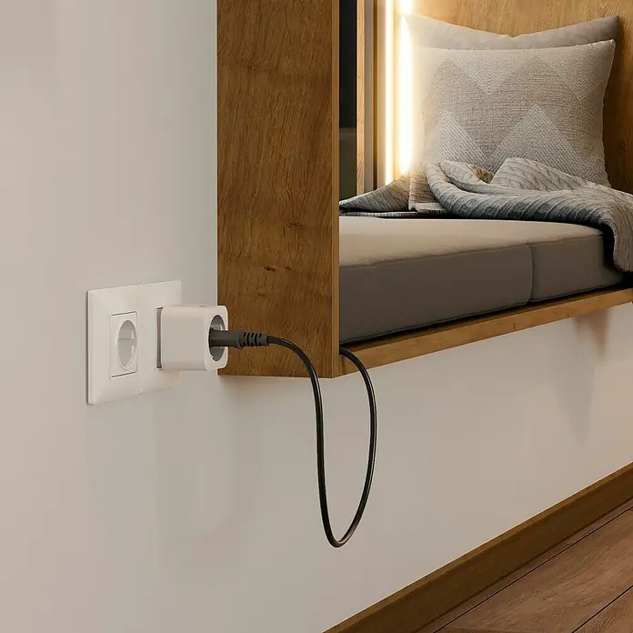 Hama Funksteckdose WLAN-Steckdose Matter - Weiß, Max. Anschlussleistung: 3.680 W, 1 Stk. - Ein weißer Steckeradapter steckt in einer Steckdose an einer weißen Wand, verbunden mit einem schwarzen Kabel.