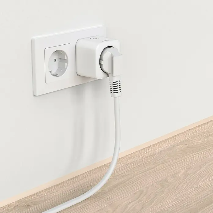 Hama Funksteckdose WLAN-Steckdose Matter - Weiß, Max. Anschlussleistung: 3.680 W, 1 Stk. - Eine weiße Steckdose an der Wand, in die ein Smart Home Zwischenstecker eingesteckt ist, mit einem weißen Kabel daran.