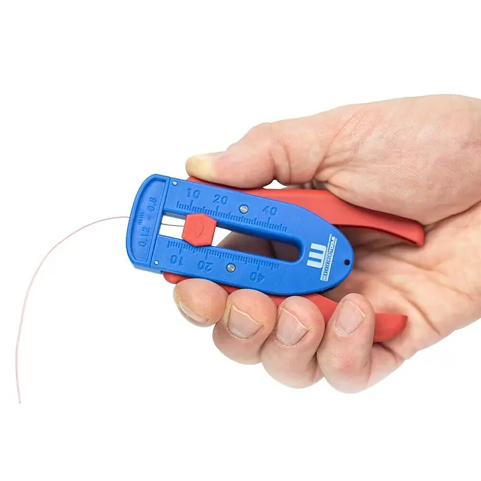 Weicon Kabelentmanteler Präzisions-Abisolierer S - Passend für: Feindrähtige Leiter und Litzen, PVC-, PTFE/Teflon-, Kynar-Isolationen von 0,12 mm - 0,8 mm - Eine Hand hält eine blaue und rote Abisolierzange mit einem pinkfarbenen Draht darin.