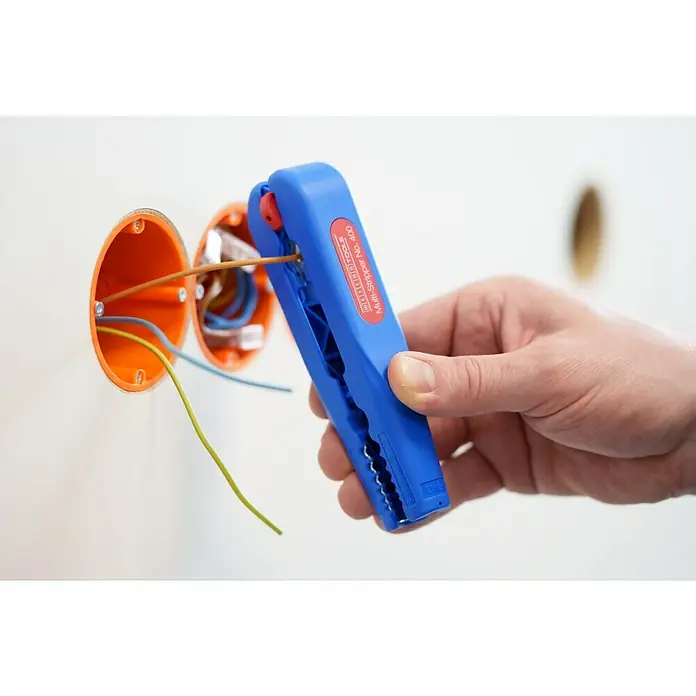 Weicon Kabelentmanteler Multi-Stripper No. 400 - 0,5 mm² - 6 mm², Blau, Rot - Draufsicht eines blauen Abisolierwerkzeugs, das von einer Hand gehalten wird, mit freiliegenden Kabeln und orangefarbenen elektrischen Anschlussdosen im Hintergrund.