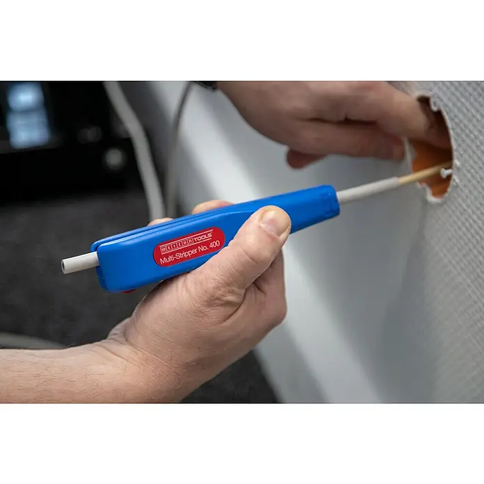Weicon Kabelentmanteler Multi-Stripper No. 400 - 0,5 mm² - 6 mm², Blau, Rot - Eine Hand hält einen blauen Weicon Tools Multi-Stripper No. 400, der in eine Wand eingeführt wird.