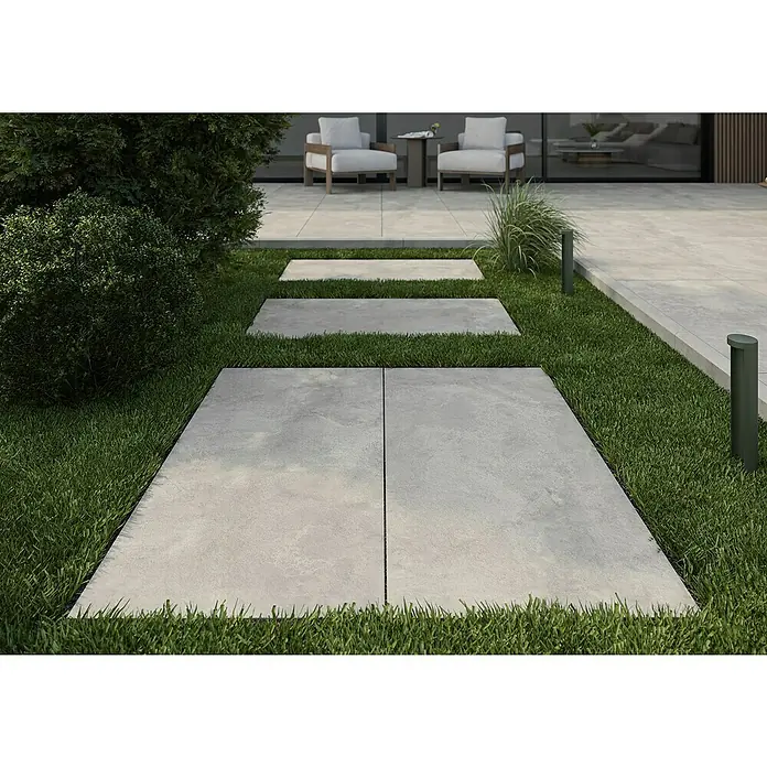 Queens Terrassenfliese - 59,3 x 119,3 x 2 cm, Grau, Matt - Bild eines Außenbereichs mit hellgrauen Terrassenplatten, die einen stilvollen Weg durch grünes Gras bilden und eine einladende Atmosphäre schaffen.