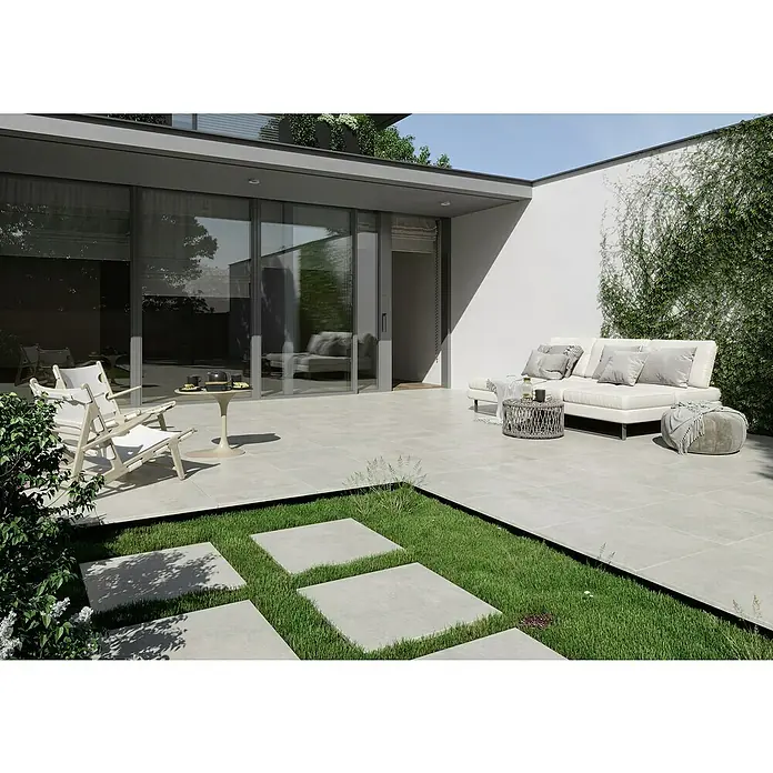 Queens Terrassenfliese - 59,3 x 119,3 x 2 cm, Weiß, Matt - Die Aufnahme zeigt ein modernes, gefliestes Außendesign mit einer Sitzgruppe und üppigem Grün, das eine entspannende Atmosphäre schafft.