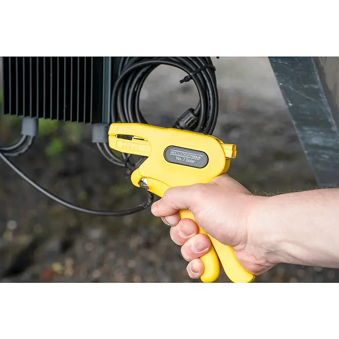 Weicon Kabelentmanteler Abisolierzange No. 7 Solar - 1,5 mm² - 10 mm², Gelb - Eine gelbe Abisolierzange „Weicon Tools No. 7 Solar“ wird von einer Hand vor einem schwarzen Kabel gehalten.