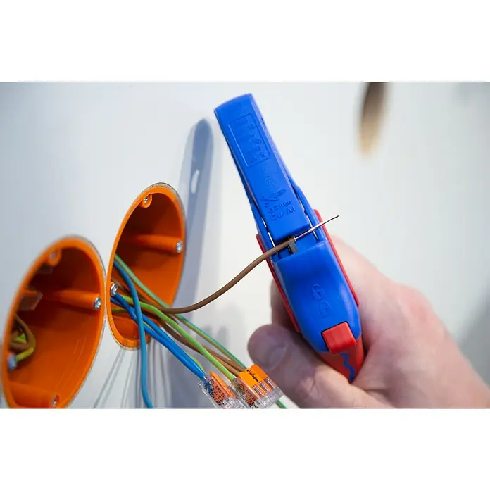 Weicon Kabelentmanteler Abisolierzange No. 5 Pro - 0,2 mm² - 16 mm², Blau, Rot - Ein blauer und roter Abisolierer wird verwendet, um ein braunes Kabel freizulegen, das sich neben einer orangefarbenen Dose befindet.