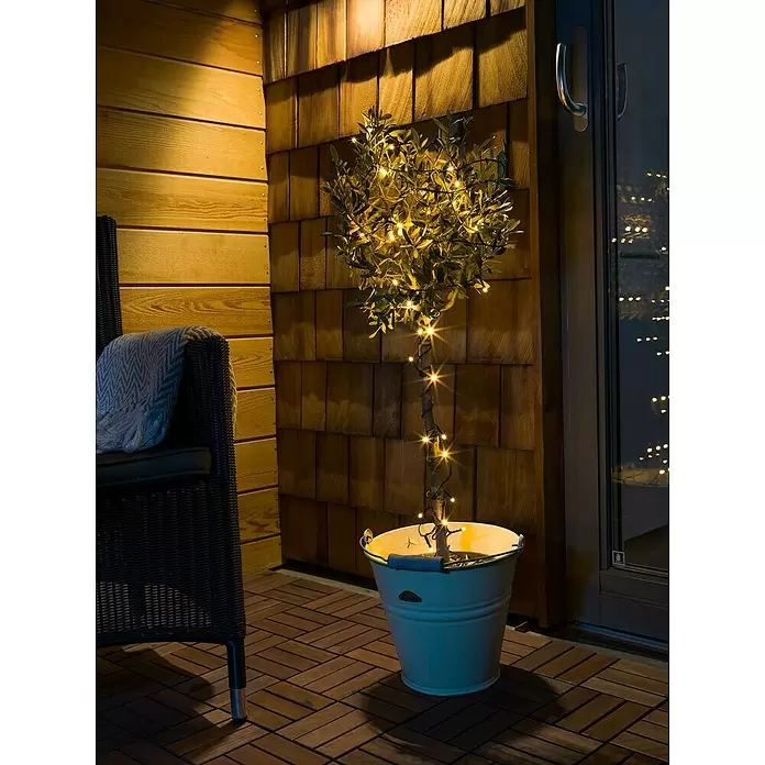 Konstsmide LED-Lichterkette - Lichtfarbe: Bernstein, Anzahl Leuchtmittel: 80 Stk., Netzbetrieben, IP44 - Topfpflanze mit warmen Lichterketten auf einer Terrasse bei Nacht für gemütliches Ambiente.