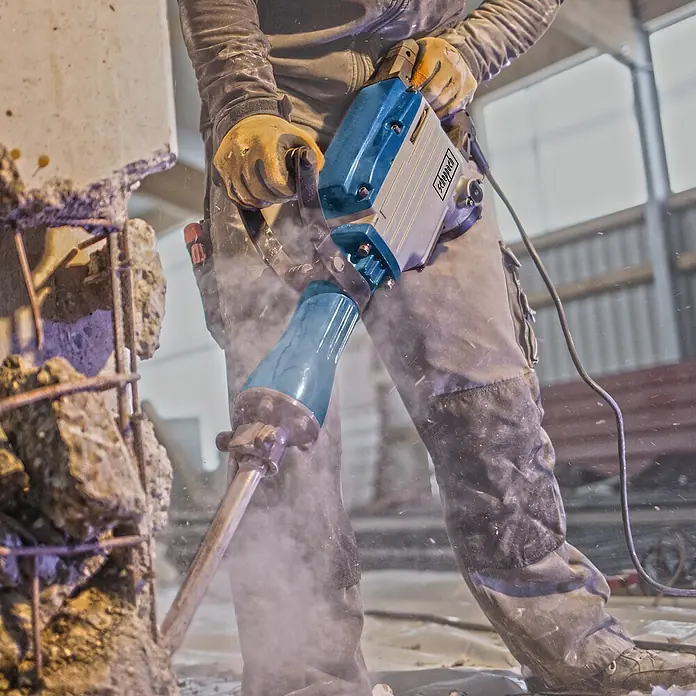 Scheppach Abbruchhammer AB 1600 - 1.600 W, 50 J, SDS-Hex-Aufnahme - Aufnahme eines Arbeiters, der einen Abbruchhammer benutzt, um einen Betonblock auf einer Baustelle einzureißen.