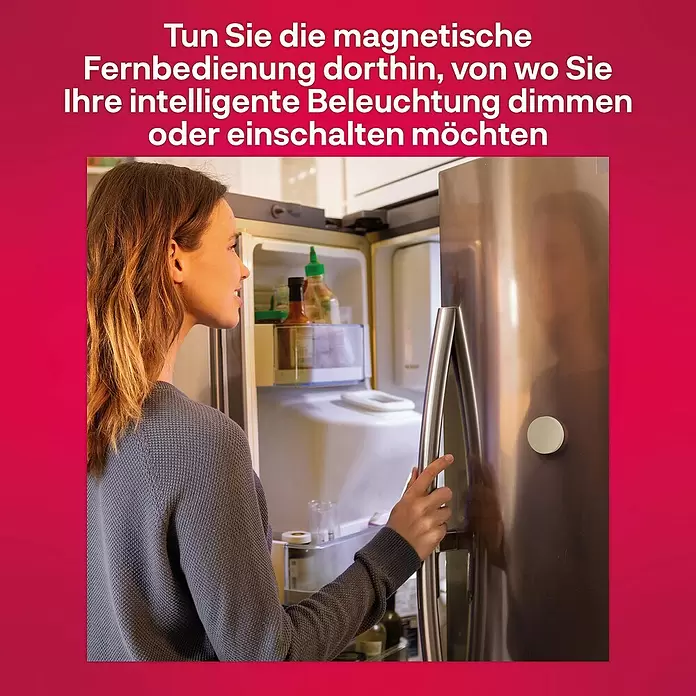 Innr Lighting Dimmcontroller Button kabellose Steuerung - Weiß - Eine Frau öffnet einen Kühlschrank, an dem ein kleiner weißer magnetischer Fernschalter für intelligente Beleuchtung haftet.