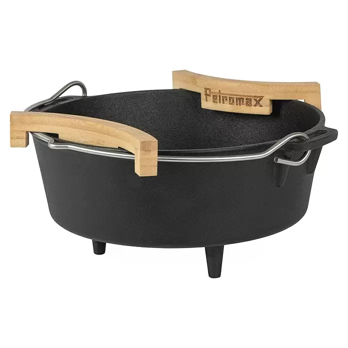 Petromax Abstandhalter für Feuertöpfe - Holz, 2 Stk. - Schwarzer gusseiserner Dutch Oven mit drei Beinen, Metallbügelgriff und zwei hölzernen Randschützern.