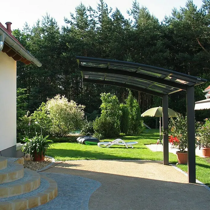 Ximax Carport Portoforte 110 - Außenmaß inkl. Dachüberstand (B x T): 2,7 x 4,95 m, Einzelcarport, Mattbraun, Schneelast: 137 kg/m² - Das Bild zeigt einen modernen Carport mit dunklem Rahmen, der Schatten spendet und das Fahrzeug schützt. Die Umgebung ist ein gepflegter Garten.